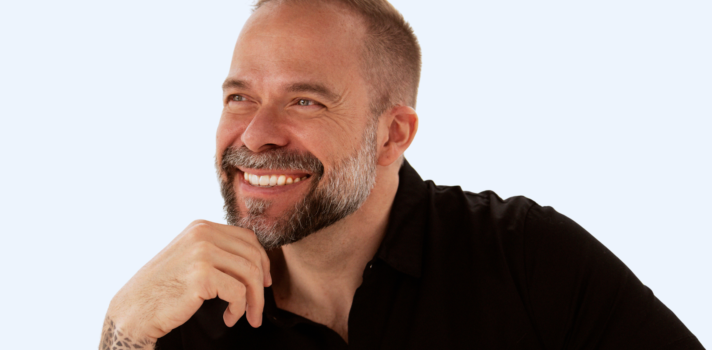 Close up portrait of a man with facial hair and a button up grey shirt