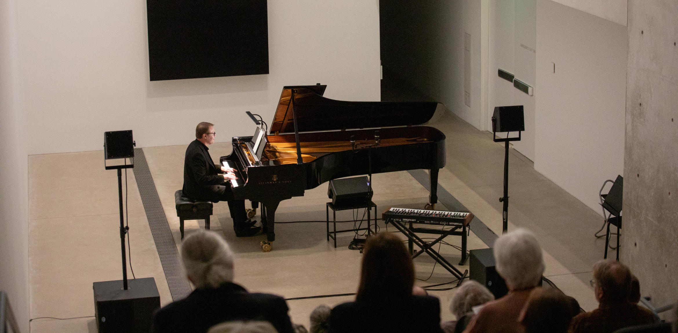 Man playing the piano at the bottom of stairs at the Pulitzer Arts Foundation to an audience